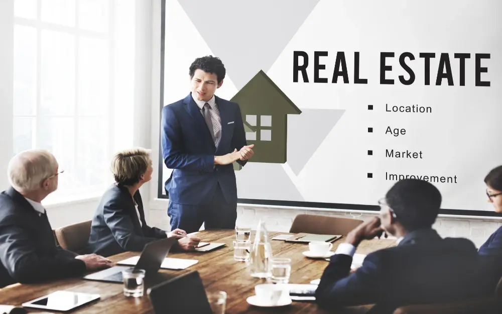 An image of a real estate agent presenting to a couple of investors the different factors to consider when considering to buy properties.